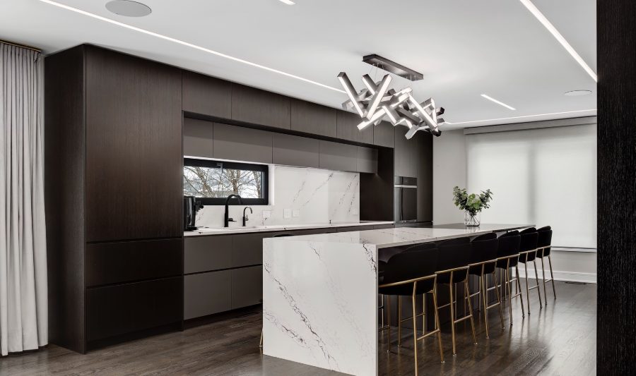 Dark wood kitchen cabinetry with a white stone waterfall island and counter seating.