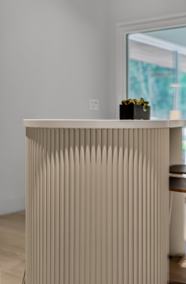 Close detail of the off-white table's half-round fluted leg beneath its rounded top.
