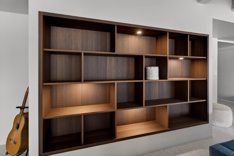 Fumed oak open shelving built into the wall, with integrated LED lighting in selected sections.